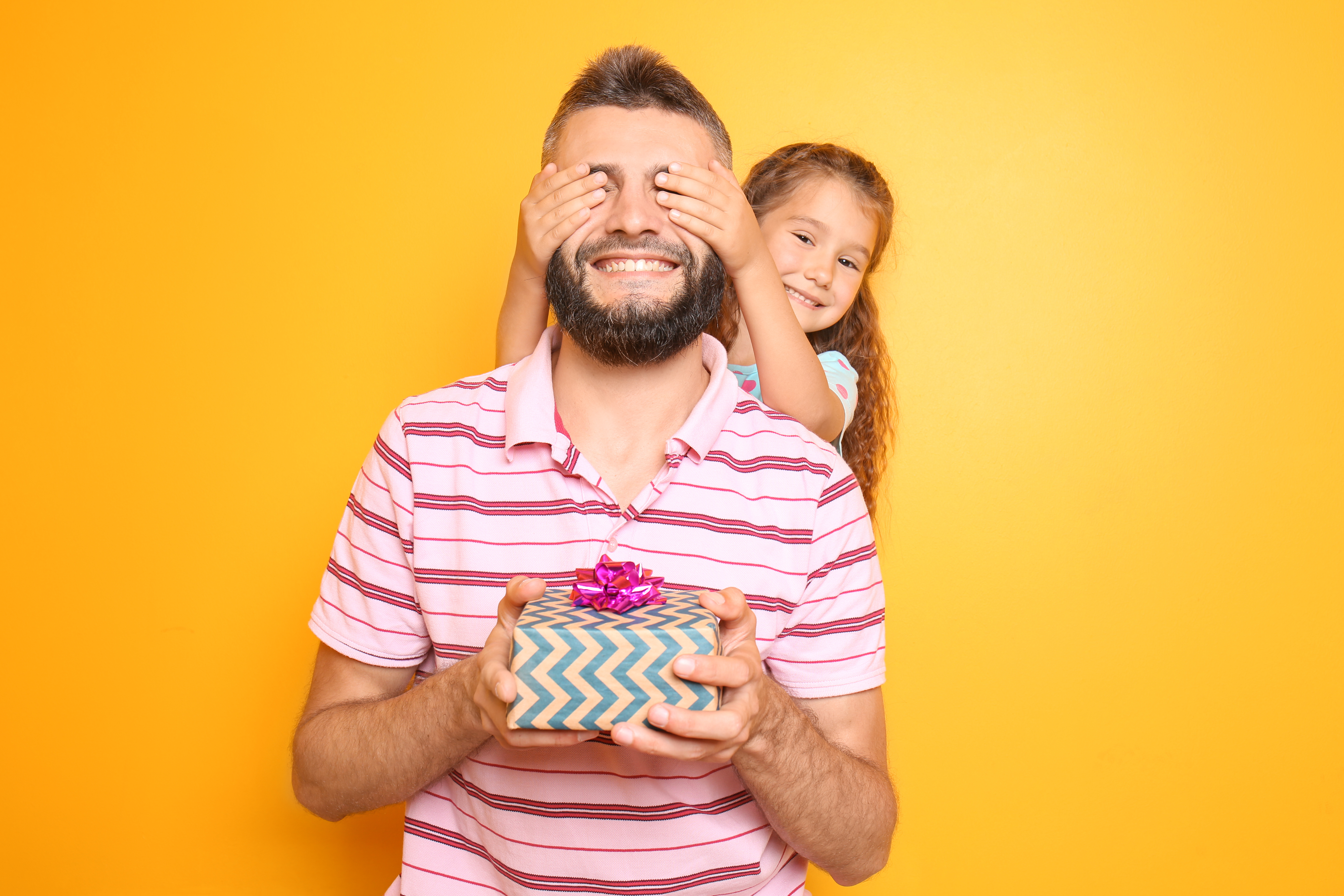 Little girl giving present to her father on color background